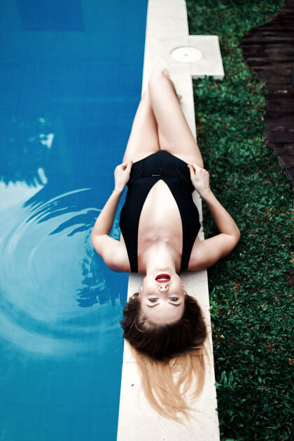 度假村美丽性感奢华的女孩躺在游泳池边 穿着黑色比基尼在热带岛屿上放松日光浴 俯瞰美景时尚人顶部