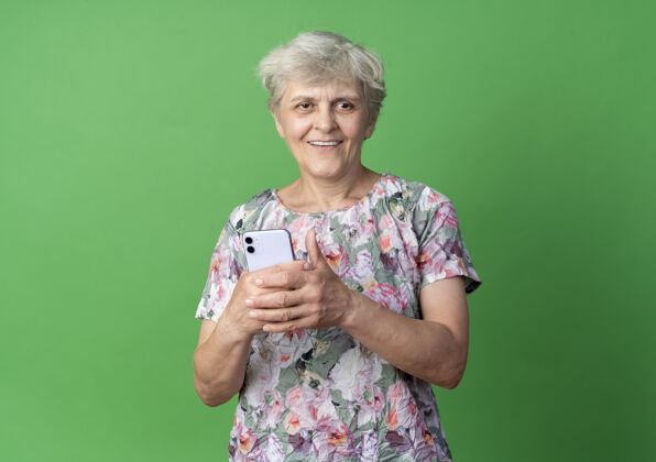 电话微笑的老妇人把电话孤立在绿色的墙上老人绿色微笑