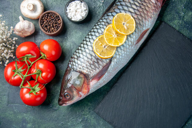 番茄在深蓝色的背景上俯瞰新鲜的生鱼片和西红柿晚餐风景肉