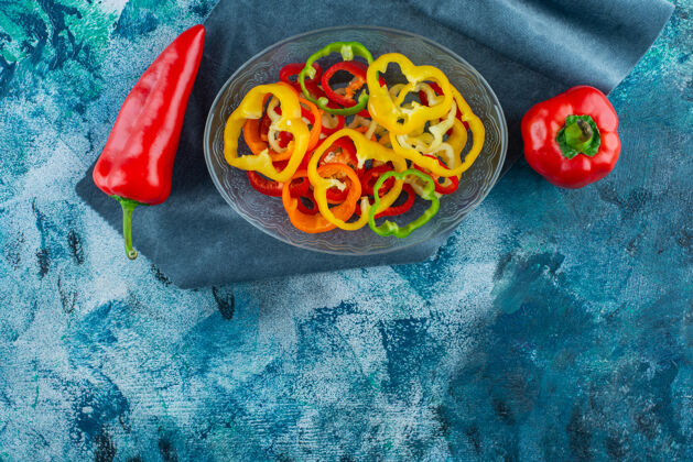 辣椒各种切碎的辣椒放在碗里 旁边是一块布上的红辣椒 背景是蓝色的碗蔬菜好吃