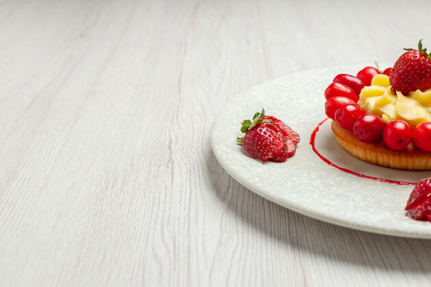 草莓正面图：白色桌上盘子里有水果的小蛋糕甜点水果蛋糕蛋糕可食用的水果奶油