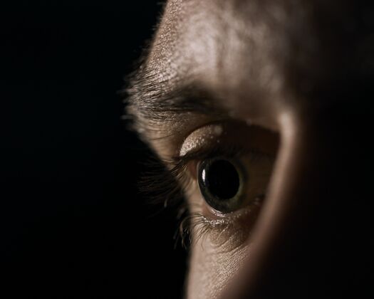 反光在黑色背景上放大瞳孔的绿色人眼特写镜头程序悲伤眼球