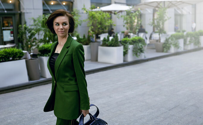 早晨走在街上的独立女士 手里拿着钱包 穿着时髦的绿色夹克 短发性感 自信又聪明散步街头商业