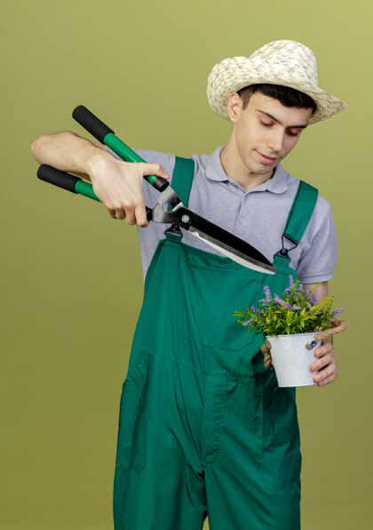 复制高兴的年轻男园丁戴着园艺帽拿着剪子在花盆上男性橄榄花盆