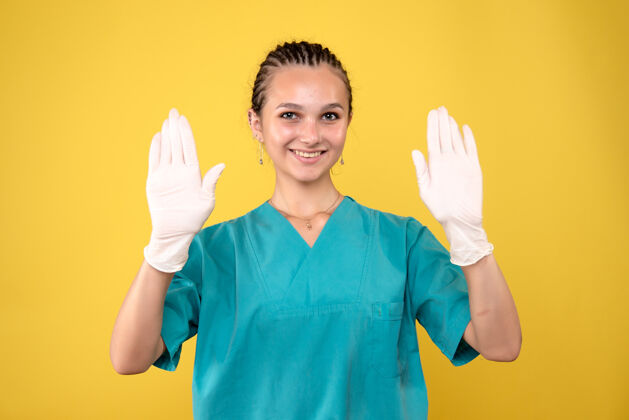 自信黄墙上戴着手套的女医生的正视图病毒女医生成人