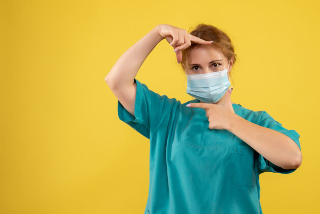 年轻女医生黄墙上年轻女医生穿着医疗服 戴着口罩的正面图护士面具医院