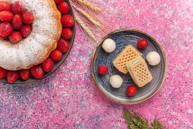 巧克力顶视图糖粉派草莓蛋糕和华夫饼上的粉红色封闭麦卡龙浆果
