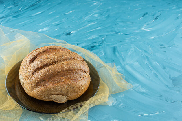 圆形一块在玻璃盘子上有皮的圆面包清淡面包食物