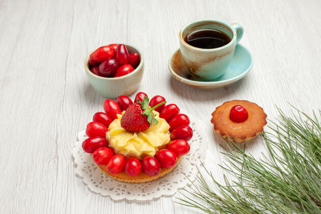 水果前视小蛋糕上的水果和茶杯上的白色桌面水果甜点彩茶甜点容器早餐