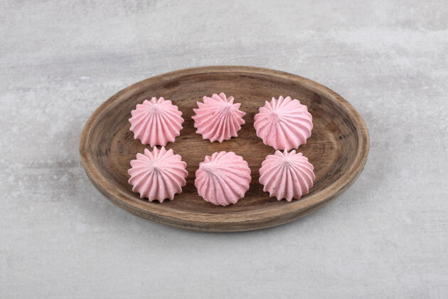 食材粉红色的蛋白酥皮放在木板上 放在大理石桌上配料糕点甜点