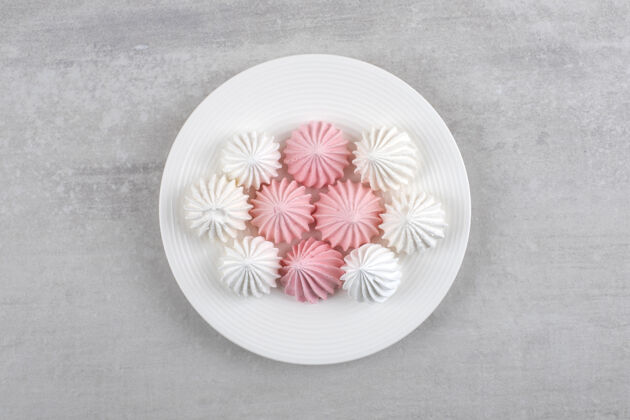 配料粉色和白色的蛋白酥皮放在白色盘子里 放在大理石桌上零食烘焙自制