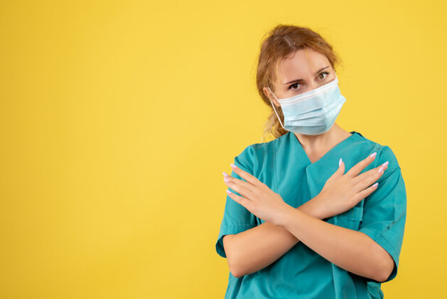成人黄墙上年轻女医生穿着医疗服 戴着口罩的正面图医院人正面