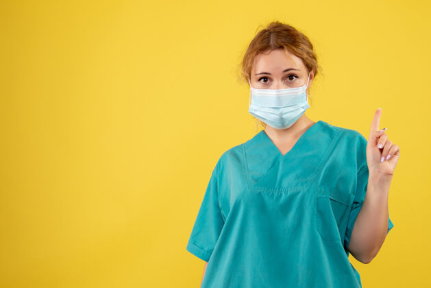 女性黄墙上年轻女医生穿着医疗服 戴着口罩的正面图成人正面面罩