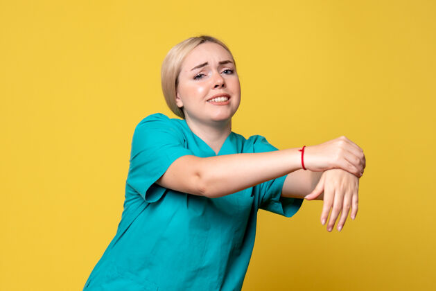 衬衫黄墙上年轻女医生穿着医用衬衫手臂受伤的正面图快乐医疗微笑