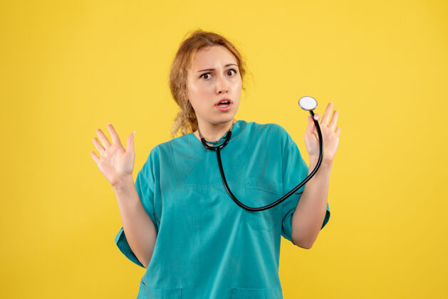 仪器黄色墙壁上穿着带听诊器的医疗服的女医生的正视图医生健康套装