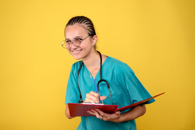 医疗器械身穿医疗衬衫的女医生在黄色墙上写笔记的正面图医疗护士书写