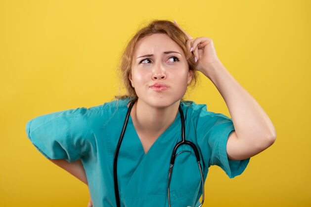 健康黄色墙壁上穿着带听诊器的医用衬衫的女医生的正视图人药护士