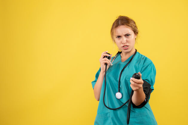 检查身穿医疗服的女医生在黄色墙壁上检查压力的正视图医疗套装压力