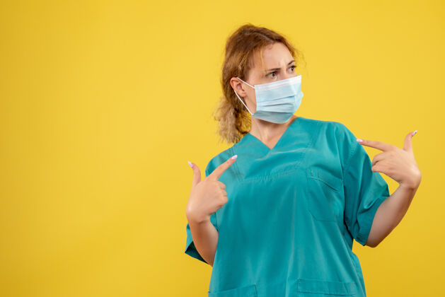 面具黄墙上年轻女医生穿着医疗服 戴着无菌口罩的正面图套装护士成人