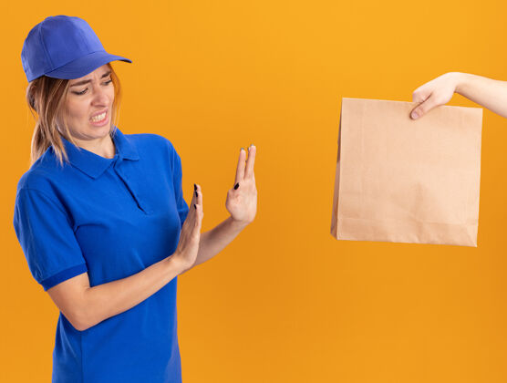 包装有人给了一个纸包给未出租的年轻漂亮的女送货员 在制服上没有橙色的标志年轻不愉快姿势