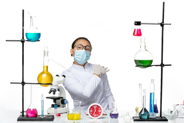 溶液前视图穿着医疗服的女化学家带着面罩坐在白色背景上 溅起了病毒化学病毒-实验室科学烧杯飞溅