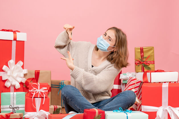 坐着正面图：年轻女性戴着面具围坐在圣诞礼物旁边房子病毒面具