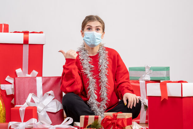 健康正面图：年轻女性戴着无菌面具坐着 手里拿着圣诞礼物人情绪成人