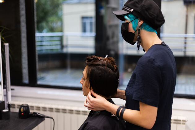 客户一个专业的女理发师给客户理发这个女孩戴着面具坐在美容院里脸设备流行