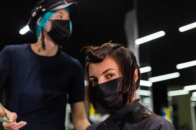 客户一个专业的女理发师给客户理发这个女孩戴着面具坐在美容院里肖像流行爆发