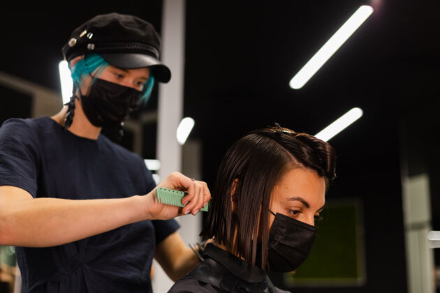 面膜一个专业的女理发师给客户理发这个女孩戴着面具坐在美容院里人理发师肖像