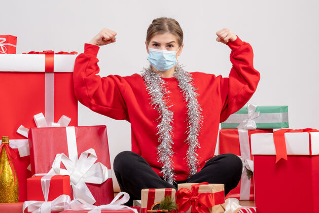 消毒正面图：年轻女性戴着无菌面具围坐在圣诞礼物旁礼物周围人