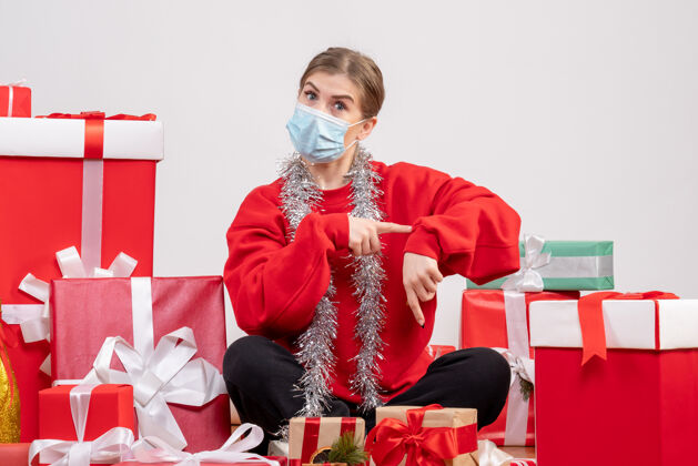 面具正面图：年轻女性戴着无菌面具坐着 手里拿着圣诞礼物人绝育圣诞节
