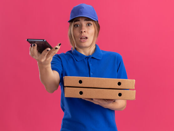 焦虑焦急的年轻漂亮的送货女孩穿着制服拿着比萨饼盒和粉红色的电话制服电话年轻
