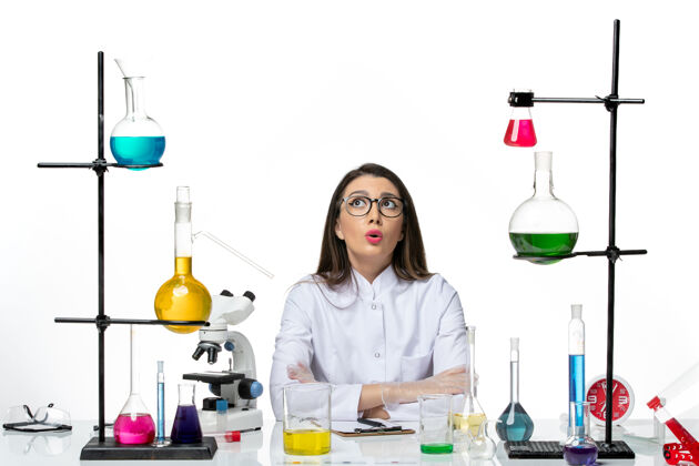 大流行前视图穿着白色医疗服的女化学家正坐在白色背景的科学病毒冠状病毒-大流行实验室里拿着溶液医疗科学实验室