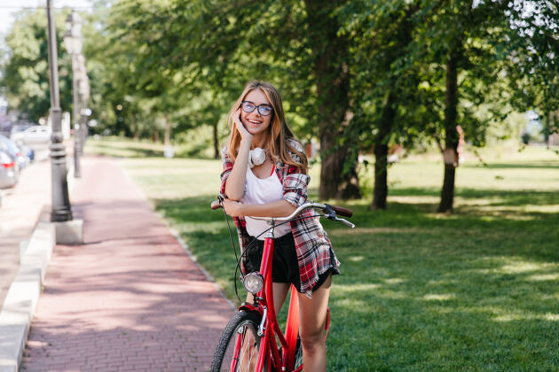 成人可爱的微笑女孩和自行车在公园里合影放松的女士在大自然中合影的户外照片人活跃年轻人