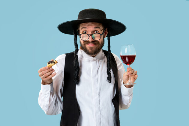 庆典这位年轻的东正教犹太男子戴着黑帽子 在犹太普瑞姆节上吃哈曼塔森饼干文化糕点宗教