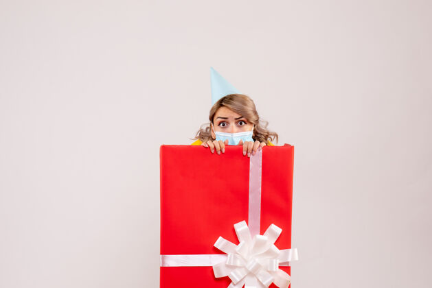 年轻女性正面图：戴着面具的红色礼品盒里的年轻女性礼物购物者盒子