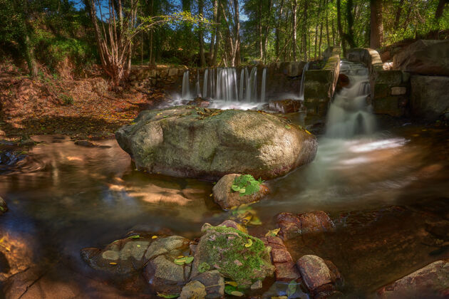 水河流长时间暴露在岩石和绿树环绕下的森林阳光下树长河流