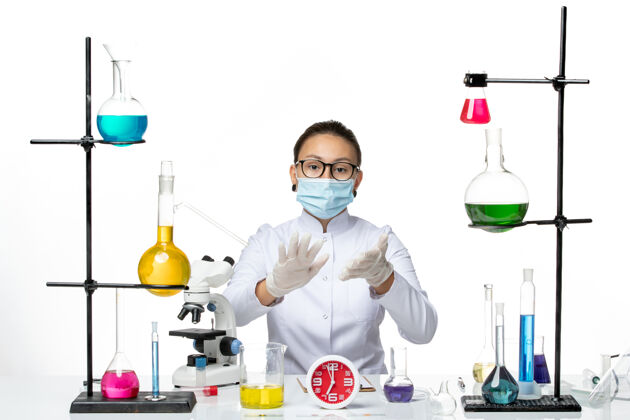 科学前视图穿着白色医疗服戴着面具的女化学家正坐在白色背景上化学家病毒冠状病毒-飞溅实验室坐化学视图