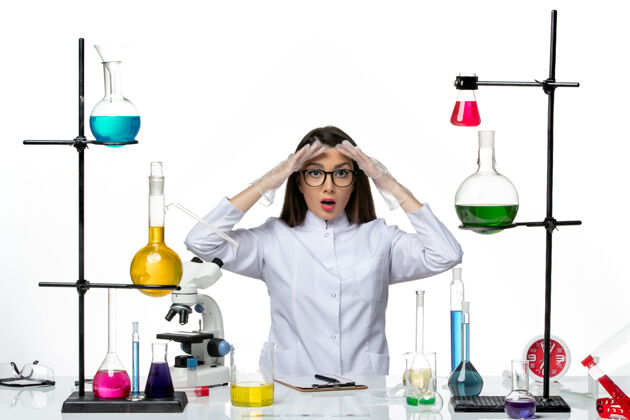 实验室前视图穿着白色医疗服的女化学家坐在白色背景的实验室里工作 研究病毒冠状病毒大流行专业烧杯化学