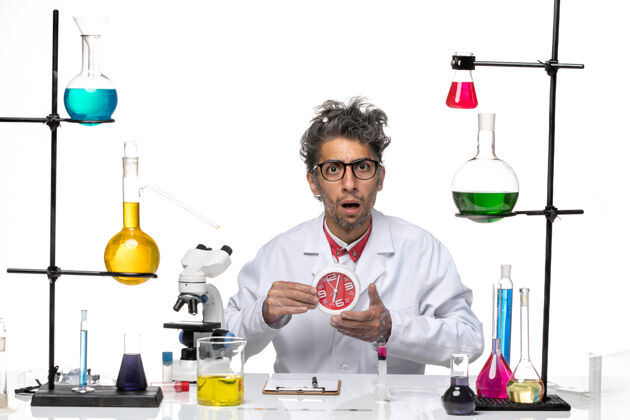 人正面图身穿医疗服的男科学家在白色办公桌上拿着24小时的时钟化学实验室病毒健康化学专业实验室