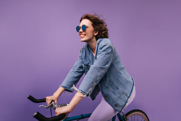 运动热情的女自行车手玩得很开心漂亮的白人女孩坐在自行车上做鬼脸快乐乐趣成人