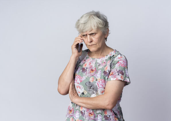 老人不高兴的老妇人在白墙上讲电话女人不高兴电话