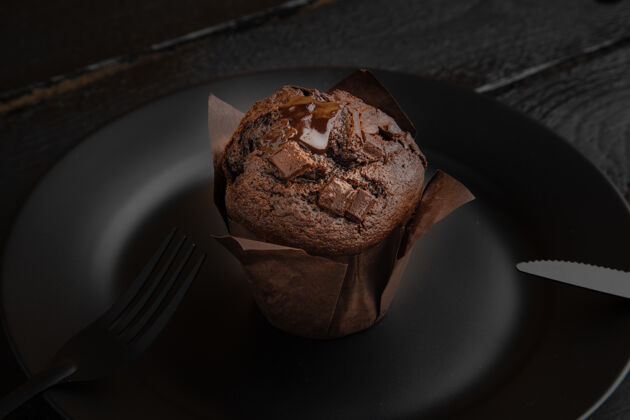 桌子黑木桌上黑色盘子上巧克力松饼的高角度拍摄新鲜木头勺子