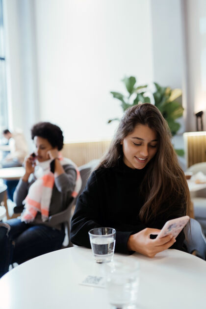 女士坐在咖啡馆里使用智能手机的女人的画像马克杯咖啡年轻