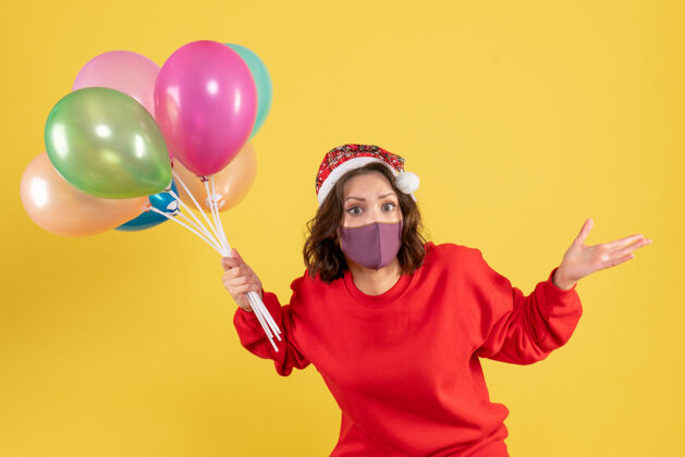 颜色正面图年轻女性拿着气球 戴着黄色的无菌面具情感聚会欢呼