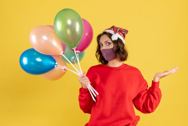 情绪正面图黄色书桌上戴着消毒面具手持气球的年轻女性新年彩女情感派对庆祝活动飞机年份年轻女性