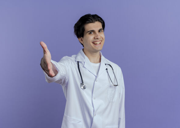 听诊器快乐的年轻男医生穿着医用长袍 戴着听诊器 看起来在做一个孤立的问候手势男人人紫色