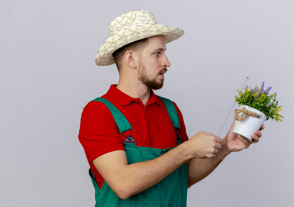 人年轻英俊的斯拉夫园丁穿着制服 戴着帽子 看着花盆 用卷尺量着它测量花园惊喜
