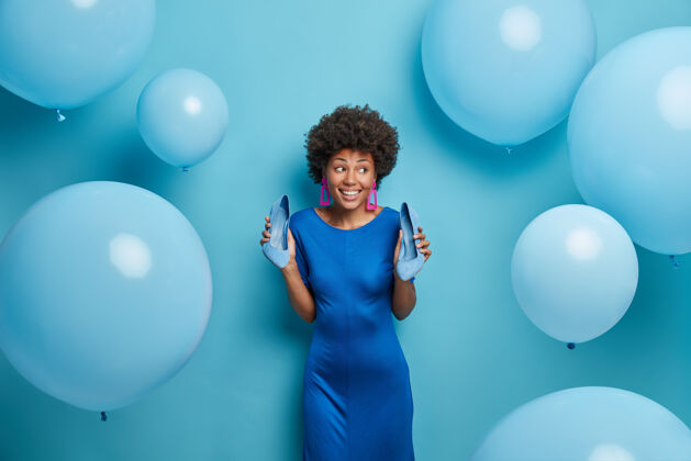 鞋子穿着蓝色连衣裙 穿着高跟鞋 享受庆典 在派对上玩得开心 微笑着看 围着气球摆姿势美国黑人女士穿着时髦的服装华丽迪斯科裙子